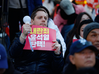 A foreign national protests in Yeouido, Seoul, South Korea, on December 8, 2024, across from the National Assembly, holding a sign that read...