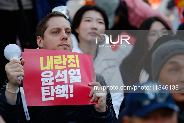 A foreign national protests in Yeouido, Seoul, South Korea, on December 8, 2024, across from the National Assembly, holding a sign that read...