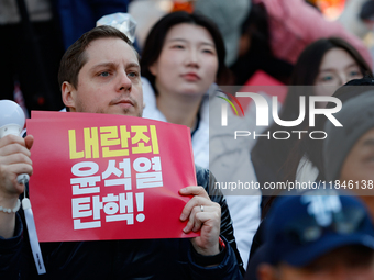 A foreign national protests in Yeouido, Seoul, South Korea, on December 8, 2024, across from the National Assembly, holding a sign that read...