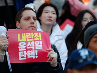 A foreign national protests in Yeouido, Seoul, South Korea, on December 8, 2024, across from the National Assembly, holding a sign that read...