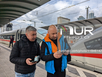 Two passengers check information at the platform in Frankfurt am Main, Hesse, Germany, on March 30, 2023. Two travelers stand on the platfor...