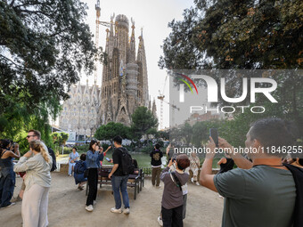 People gather in a park near the cathedral of the Sagrada Familia in Barcelona, Spain, on October 09, 2024. This monument, designed by archi...