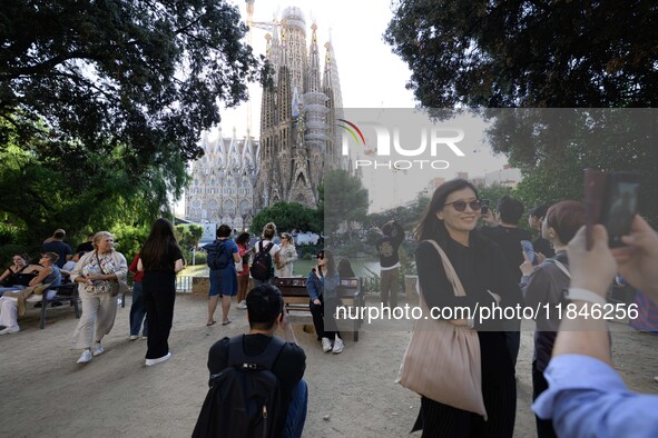 People gather in a park near the cathedral of the Sagrada Familia in Barcelona, Spain, on October 09, 2024. This monument, designed by archi...