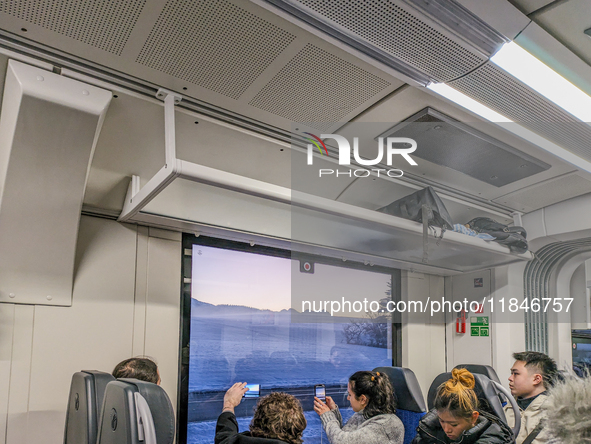 Asian travelers admire the Bavarian winter landscapes. On a train journey to Füssen, Bavaria, Germany, on January 13, 2024, a group of Asian...