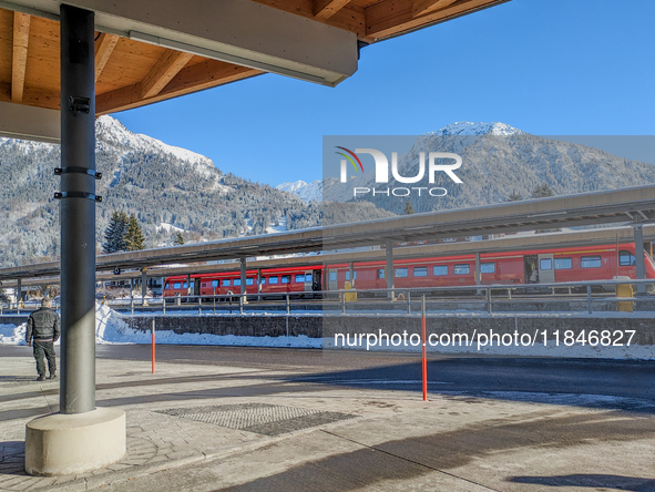 A red regional train stands at the platform at Oberstdorf train station in Schwaben, Oberallgau, Bavaria, Germany, on January 20, 2024, with...