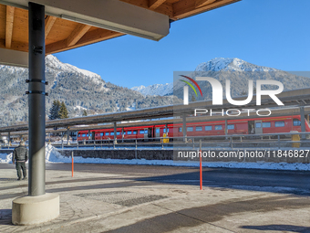 A red regional train stands at the platform at Oberstdorf train station in Schwaben, Oberallgau, Bavaria, Germany, on January 20, 2024, with...