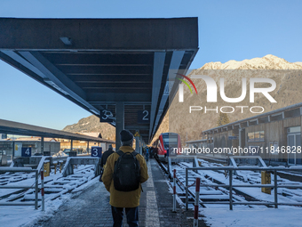 At Oberstdorf train station in Swabia, Upper Allgaeu, Bavaria, Germany, on January 20, 2024, a traveler stands on the snow-covered platform...