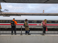 Three travelers stand on a platform at Munich Pasing Station in Bavaria, Germany, on November 15, 2024, looking towards an ICE train situate...