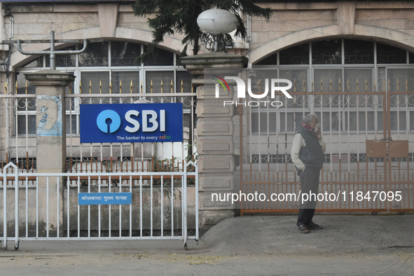 A person stands next to an SBI bank branch in Kolkata, India, on December 8, 2024. 