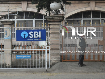 A person stands next to an SBI bank branch in Kolkata, India, on December 8, 2024. (