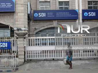 A person passes next to an SBI bank branch in Kolkata, India, on December 8, 2024. (