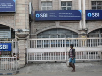 A person passes next to an SBI bank branch in Kolkata, India, on December 8, 2024. (