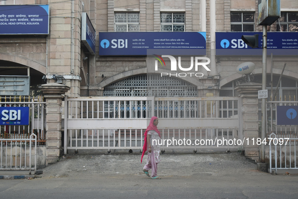 A woman passes next to an SBI bank branch in Kolkata, India, on December 8, 2024. 