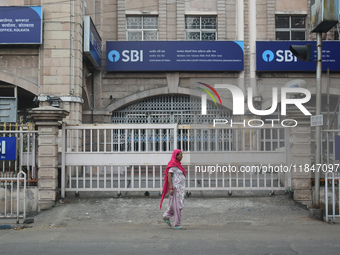 A woman passes next to an SBI bank branch in Kolkata, India, on December 8, 2024. (