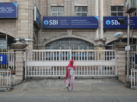 A woman passes next to an SBI bank branch in Kolkata, India, on December 8, 2024. (