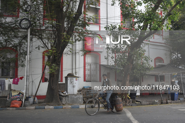 A person carries gas cylinders on his cycle while passing next to a foreign post office in Kolkata, India, on December 8, 2024. 