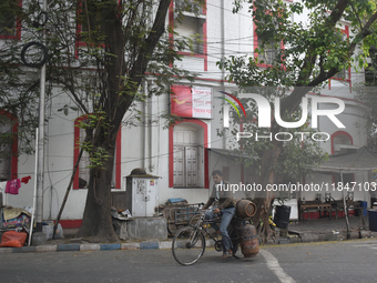 A person carries gas cylinders on his cycle while passing next to a foreign post office in Kolkata, India, on December 8, 2024. (