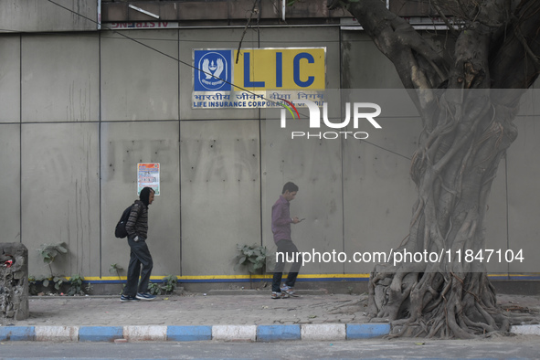 People pass next to an LIC branch in Kolkata, India, on December 8, 2024. 