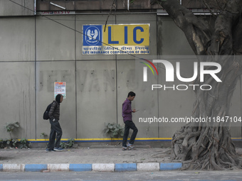 People pass next to an LIC branch in Kolkata, India, on December 8, 2024. (