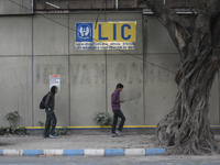 People pass next to an LIC branch in Kolkata, India, on December 8, 2024. (