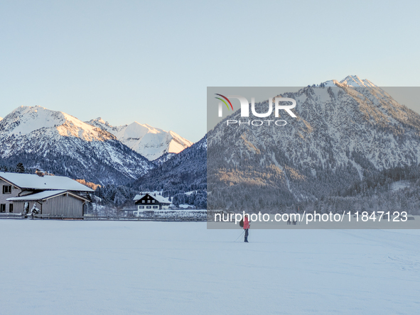 In Oberstdorf, Bavaria, Germany, on January 20, 2024, skiers glide across a flat, snow-covered trail surrounded by alpine scenery. The snow-...