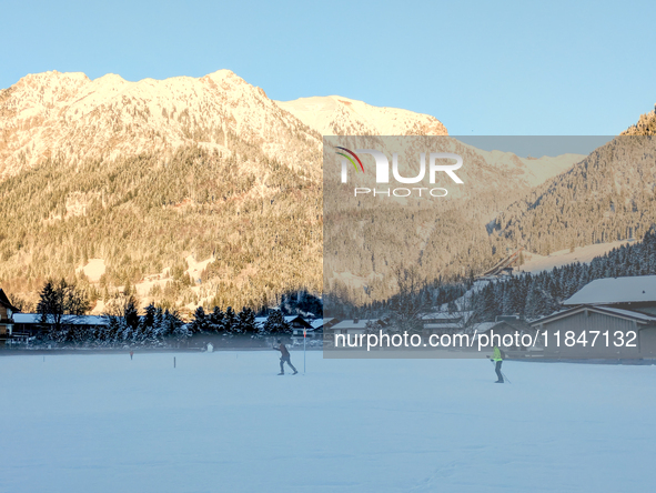 In Oberstdorf, Bavaria, Germany, on January 20, 2024, skiers glide across a flat, snow-covered trail surrounded by alpine scenery. The snow-...