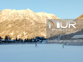 In Oberstdorf, Bavaria, Germany, on January 20, 2024, skiers glide across a flat, snow-covered trail surrounded by alpine scenery. The snow-...