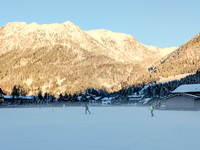 In Oberstdorf, Bavaria, Germany, on January 20, 2024, skiers glide across a flat, snow-covered trail surrounded by alpine scenery. The snow-...