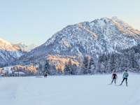 In Oberstdorf, Bavaria, Germany, on January 20, 2024, skiers glide across a flat, snow-covered trail surrounded by alpine scenery. The snow-...