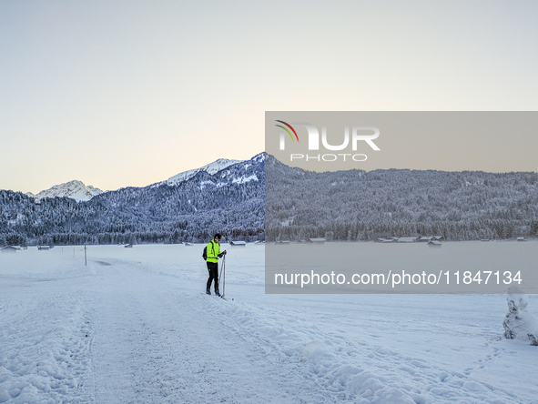 In Oberstdorf, Bavaria, Germany, on January 20, 2024, skiers glide across a flat, snow-covered trail surrounded by alpine scenery. The snow-...