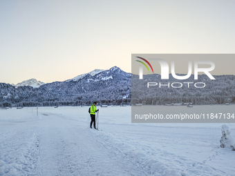 In Oberstdorf, Bavaria, Germany, on January 20, 2024, skiers glide across a flat, snow-covered trail surrounded by alpine scenery. The snow-...