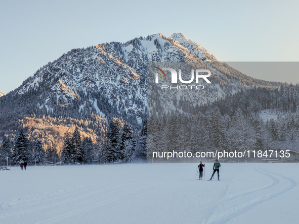 In Oberstdorf, Bavaria, Germany, on January 20, 2024, skiers glide across a flat, snow-covered trail surrounded by alpine scenery. The snow-...