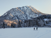 In Oberstdorf, Bavaria, Germany, on January 20, 2024, skiers glide across a flat, snow-covered trail surrounded by alpine scenery. The snow-...