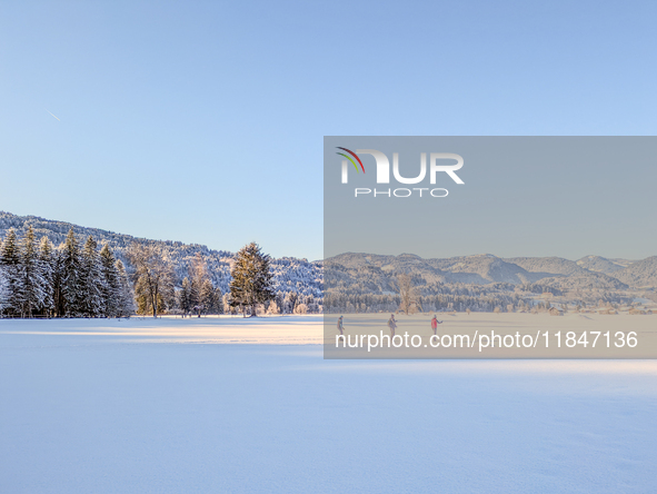 In Oberstdorf, Bavaria, Germany, on January 20, 2024, skiers glide across a flat, snow-covered trail surrounded by alpine scenery. The snow-...