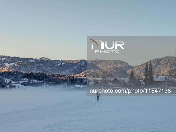 In Oberstdorf, Bavaria, Germany, on January 20, 2024, skiers glide across a flat, snow-covered trail surrounded by alpine scenery. The snow-...