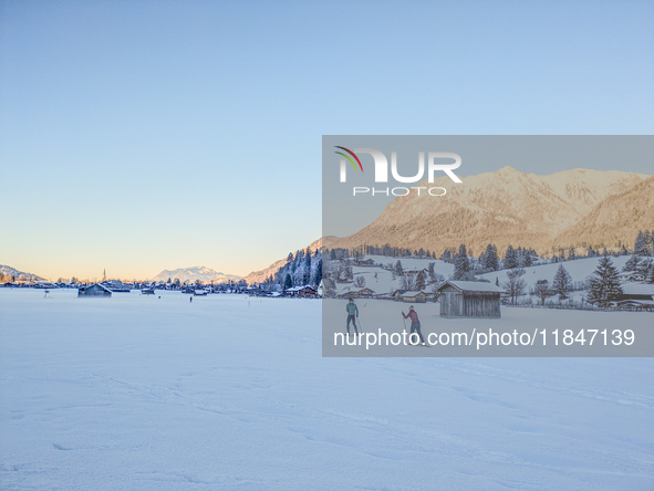 In Oberstdorf, Bavaria, Germany, on January 20, 2024, skiers glide across a flat, snow-covered trail surrounded by alpine scenery. The snow-...