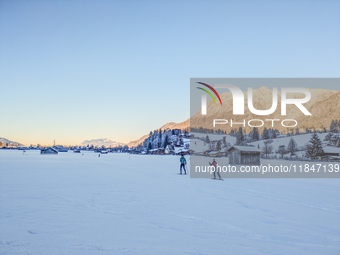 In Oberstdorf, Bavaria, Germany, on January 20, 2024, skiers glide across a flat, snow-covered trail surrounded by alpine scenery. The snow-...