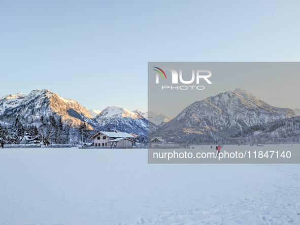 In Oberstdorf, Bavaria, Germany, on January 20, 2024, skiers glide across a flat, snow-covered trail surrounded by alpine scenery. The snow-...