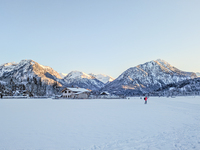 In Oberstdorf, Bavaria, Germany, on January 20, 2024, skiers glide across a flat, snow-covered trail surrounded by alpine scenery. The snow-...