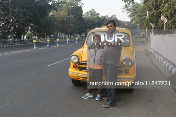 Shambhu Prasad, a yellow taxi driver, takes a selfie with his son along his yellow taxi in front of Eaden Gardens in Kolkata, India, on Dece...