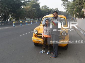 Shambhu Prasad, a yellow taxi driver, takes a selfie with his son along his yellow taxi in front of Eaden Gardens in Kolkata, India, on Dece...