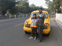 Shambhu Prasad, a yellow taxi driver, takes a selfie with his son along his yellow taxi in front of Eaden Gardens in Kolkata, India, on Dece...