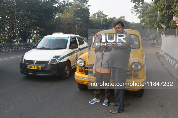 Shambhu Prasad, a yellow taxi driver, takes a selfie with his son along his yellow taxi in front of Eaden Gardens in Kolkata, India, on Dece...