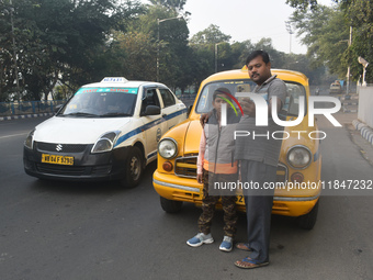 Shambhu Prasad, a yellow taxi driver, takes a selfie with his son along his yellow taxi in front of Eaden Gardens in Kolkata, India, on Dece...