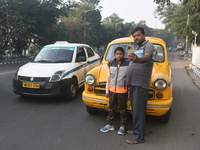 Shambhu Prasad, a yellow taxi driver, takes a selfie with his son along his yellow taxi in front of Eaden Gardens in Kolkata, India, on Dece...