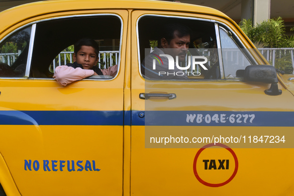 Shambhu Prasad, a yellow taxi driver, travels with his son in his yellow taxi in Kolkata, India, on December 8, 2024. Kolkata says goodbye t...