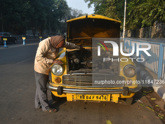 Akshil Yadav, a yellow taxi driver, checks his yellow taxi in Kolkata, India, on December 8, 2024. Kolkata says goodbye to its yellow taxis....