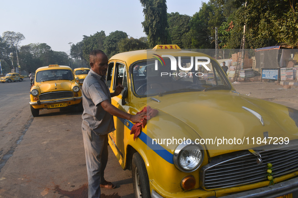 Babulal Prasad, a yellow taxi driver, cleans his taxi in Kolkata, India, on December 8, 2024. Kolkata says goodbye to its yellow taxis. A co...