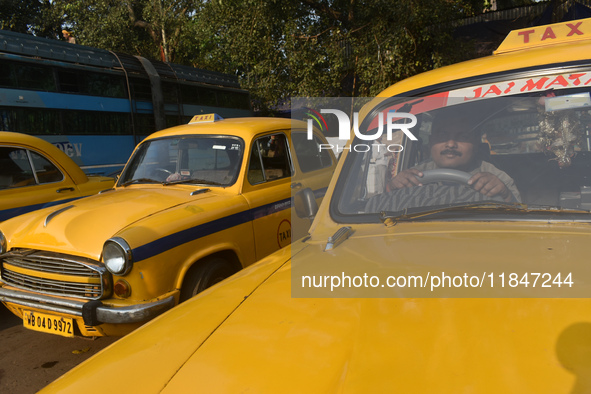 A yellow taxi driver sits inside his taxi and waits for passengers at a taxi stand in Kolkata, India, on December 8, 2024. Kolkata says good...