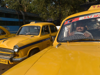 A yellow taxi driver sits inside his taxi and waits for passengers at a taxi stand in Kolkata, India, on December 8, 2024. Kolkata says good...